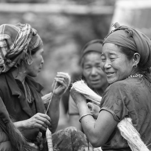 Village women talking about secret women's business while hand weaving yarn